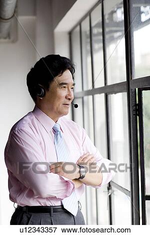 Stock Photo - Businessman wearing headset by window. Fotosearch