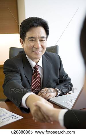 Stock Photography - Businesspeople shaking hands in the office. Fotosearch