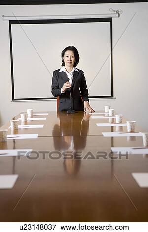 Stock Photo - Businesswoman at head of table in boardroom, portrait. Fotosearch