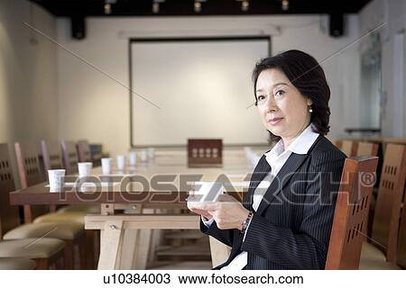 Businesswoman holding a cup of coffee in board room View Large Photo Image Stock Image - Businesswoman holding a cup of coffee in board room. Fotosearch