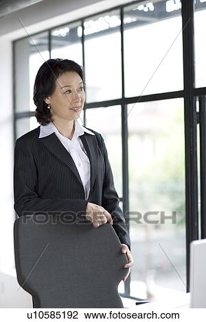 Businesswoman leaning on chair by window View Large Photo Image Stock Image - Businesswoman leaning on chair by window. Fotosearch