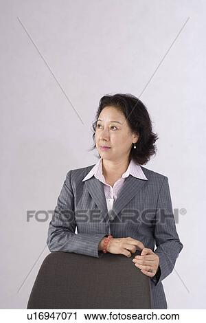 Businesswoman leaning on chair in studio shot View Large Photo Image Stock Image - Businesswoman leaning on chair in studio shot. Fotosearch