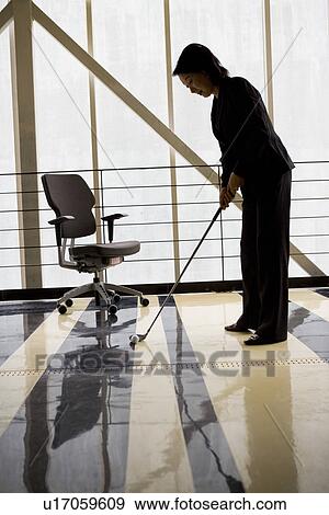 Stock Photo - Businesswoman playing golf in office. Fotosearch
