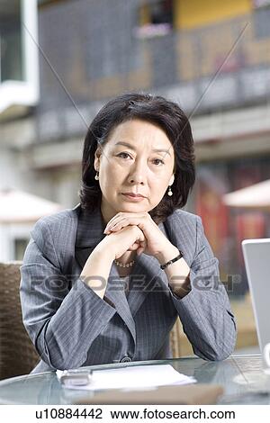 Stock Image - Businesswoman sitting at outdoors coffee shop. Fotosearch