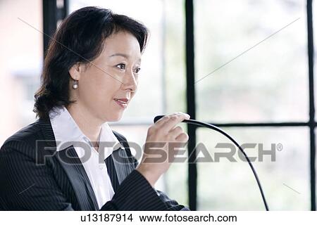 Picture - Businesswoman talking on microphone. Fotosearch