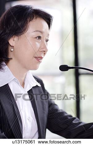 Stock Image - Businesswoman talking on microphone. Fotosearch
