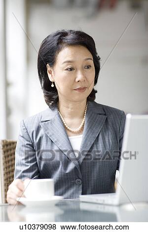 Stock Photo - Businesswoman using laptop at coffee shop. Fotosearch