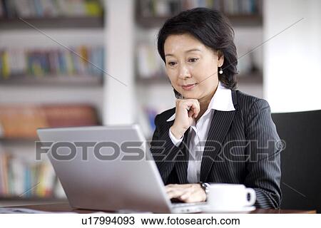 Stock Image - Businesswoman using laptop in office. Fotosearch