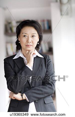 Businesswoman with hand on chin in office View Large Photo Image Stock Photo - Businesswoman with hand on chin in office. Fotosearch