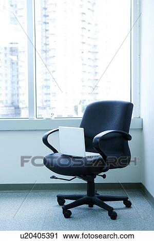 Stock Image - Laptop in chair at corner of office. Fotosearch