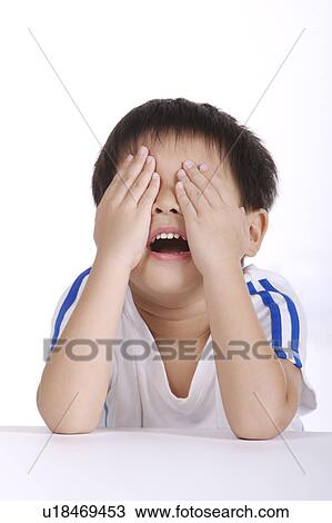 Stock Image - Boy covering face with hands, close-up. Fotosearch