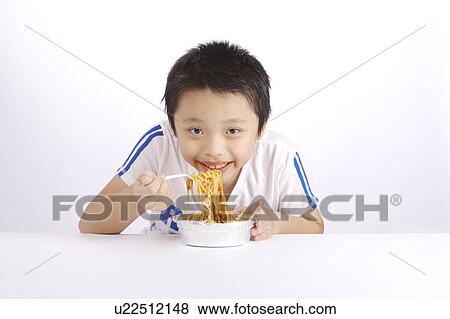 Stock Photo - Boy eating noodles, portrait. Fotosearch