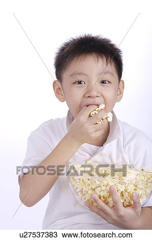 Stock Image - Boy eating popcorn, close up, portrait. Fotosearch