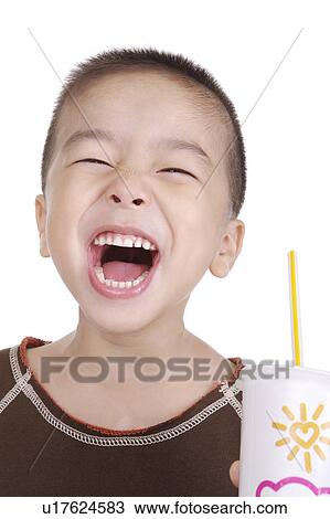 Stock Image - Boy holding drinks smiling, portrait. Fotosearch