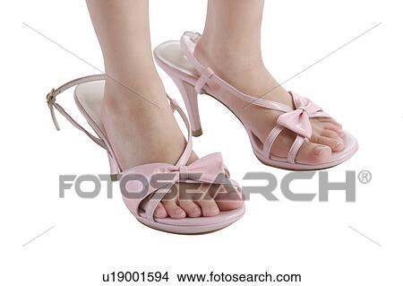 Picture - Girl standing on pair of red high heels, low section. Fotosearch