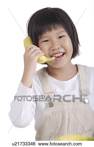Stock Photograph - Girl using banana as telephone. Fotosearch