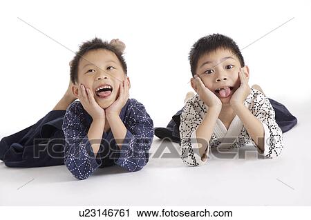 Stock Image - Two boys lying on floor, portrait, close up. Fotosearch