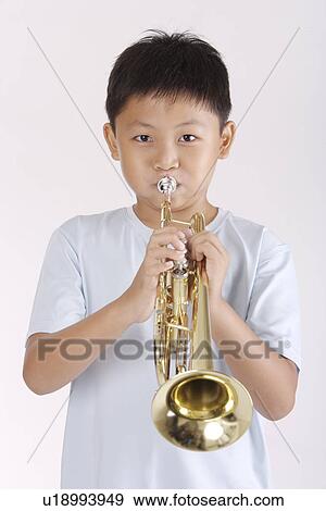 Stock Photo - Boy blowing trumpet, portrait. Fotosearch