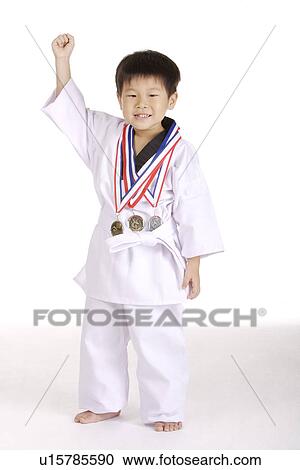 Stock Image - Boy in taekwondo uniform with three medals. Fotosearch