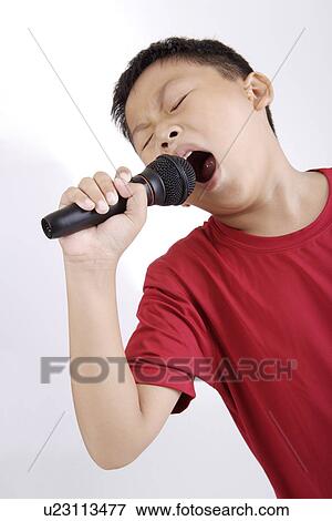 Stock Photo - Boy singing with microphone, portrait. Fotosearch