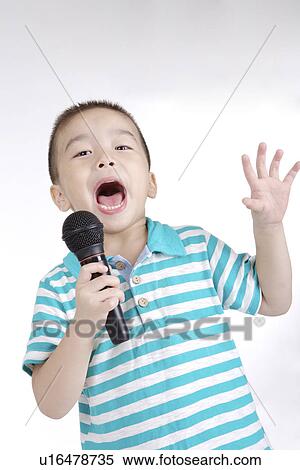 Stock Photography - Boy singing with microphone, portrait. Fotosearch