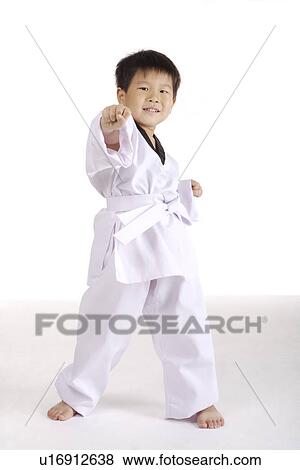 Stock Photo - Boy wearing taekwondo uniform punching the air, portrait. Fotosearch
