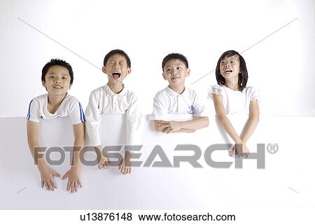 Stock Photo - Four children by table, portrait. Fotosearch