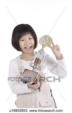 Stock Image - Girl holding trophy, smiling, portrait. Fotosearch