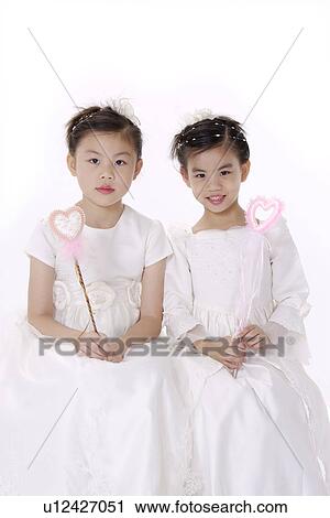 Stock Image - Two girls wearing formal dress with magic wand. Fotosearch