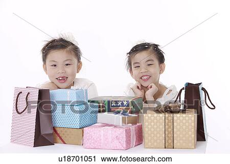 Stock Image - Two girls with stack of gifts. Fotosearch