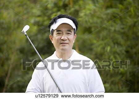Stock Photo - Senior man holding golf club outdoors. Fotosearch