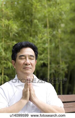 Stock Photo - Senior man in prayer position outdoors. Fotosearch