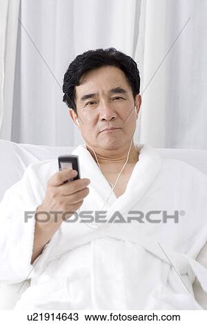 Stock Image - Senior man listening music from mobile phone. Fotosearch