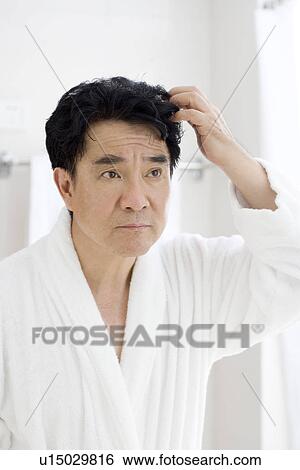 Stock Photograph - Senior man looking in mirror in bathroom. Fotosearch