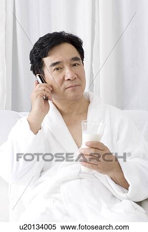 Stock Photography - Senior man on the phone sitting on sofa. Fotosearch