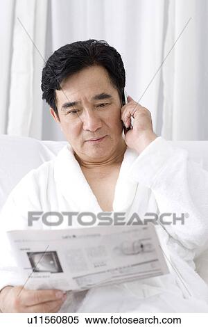 Senior man on the phone while reading newspaper View Large Photo Image Stock Photography - Senior man on the phone while reading newspaper. Fotosearch