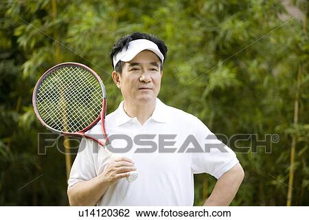 Stock Image - Senior man with tennis racket, smiling, portrait. Fotosearch