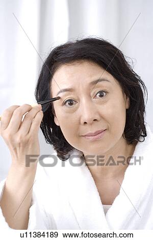 Stock Photo - Senior woman applying eyeshadow. Fotosearch