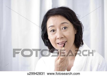 Stock Image - Senior woman applying lipstick. Fotosearch