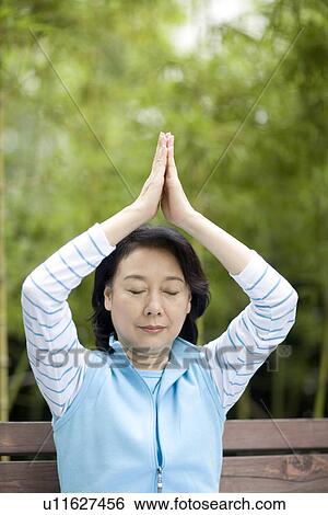 Stock Photograph - Senior woman in prayer position outdoors. Fotosearch