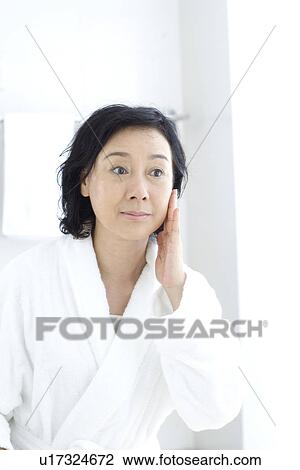 Senior woman touching face in bathroom View Large Photo Image Stock Image - Senior woman touching face in bathroom. Fotosearch
