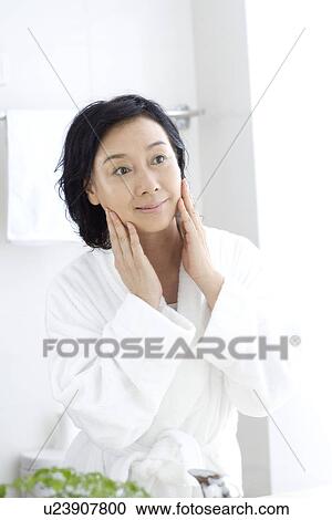 Senior woman touching face in bathroom View Large Photo Image Stock Image - Senior woman touching face in bathroom. Fotosearch