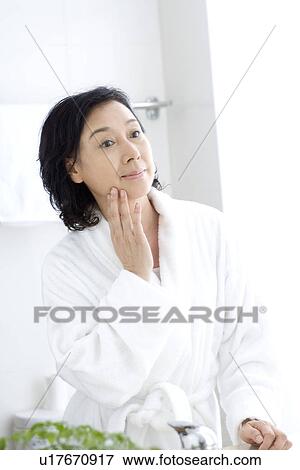 Senior woman touching face in bathroom View Large Photo Image Stock Photo - Senior woman touching face in bathroom. Fotosearch