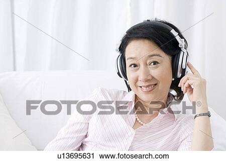 Stock Image - Senior woman wearing headset indoors. Fotosearch