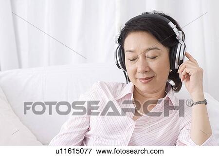 Stock Photo - Senior woman wearing headset listening music. Fotosearch