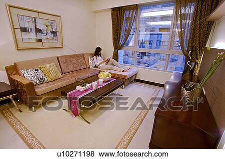 Stock Photo - Young woman in living room. Fotosearch