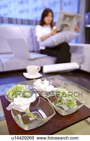 Stock Photo - Young woman reading newspaper, Flowers Arrangement in the foreground. Fotosearch