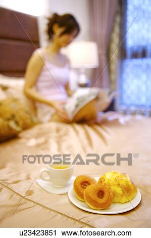 Young woman sitting on bed reading book View Large Photo Image Stock Image - Young woman sitting on bed reading book. Fotosearch
