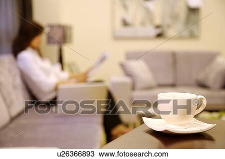 Young woman sitting on sofa, teacup in the foreground View Large Photo Image Stock Image - Young woman sitting on sofa, teacup in the foreground. Fotosearch