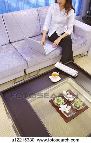 Young woman using laptop in living room View Large Photo Image Stock Image - Young woman using laptop in living room. Fotosearch